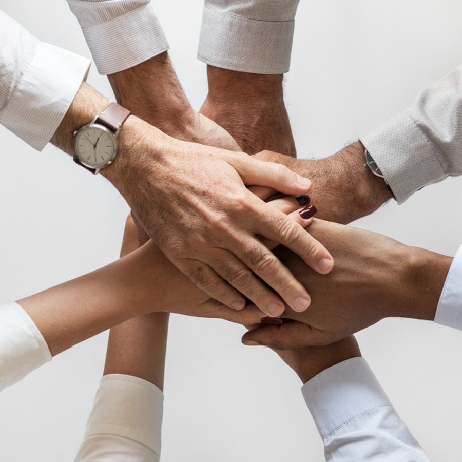 Equipe com as mãos unidas, representando trabalho em conjunto